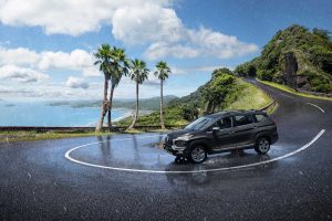Mitsubishi Xpander 2024 en México - color gris, diseño exterior, recorriendo en carretera en curva con playa a lo lejos y palmeras