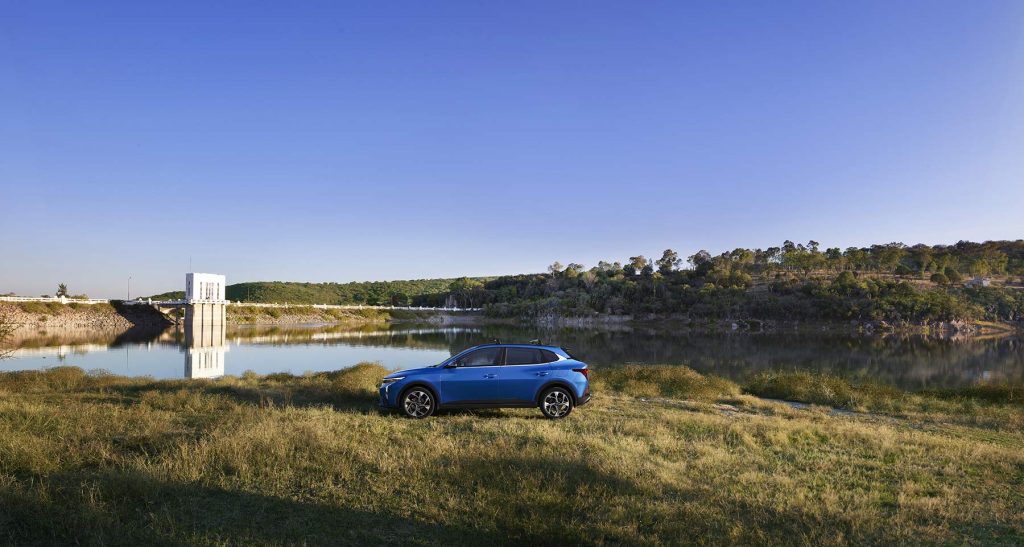 Kia K3 Hatchback 2024 en México - diseño exterior lateral en campo y un lago al fondo